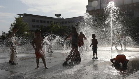Niños se refrescan con el agua en la plaza de Yamaguchi de Pamplona, en una imagen tomada el pasado 6 de agosto.