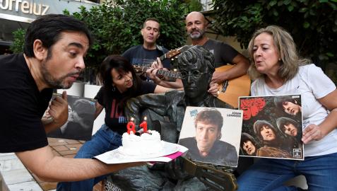 El periodista Adolfo Iglesias, autor del libro 'Juan y John, el profesor y Lennon en Almería para siempre' celebra junto a varios aficionados a los Beatles, el 81 cumpleaños del John Lennon, frente a la estatua del musico inglés en Almería.