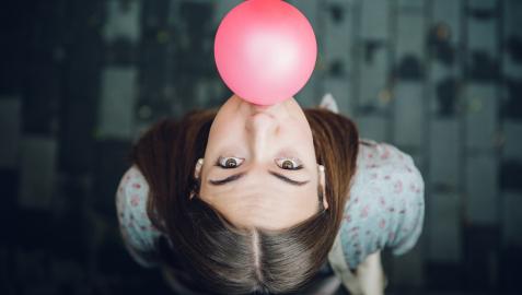 Una joven hace una pompa con un chicle