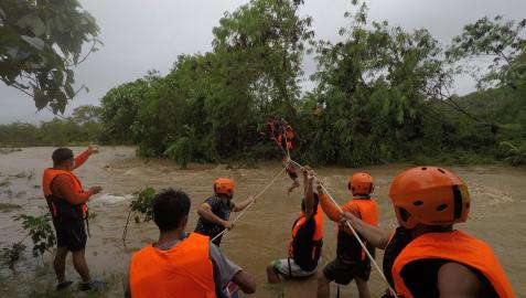Equipos de rescate ayudan a una persona a pasar sobre un río en la provincia filipina de Gonzaga