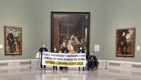 Víctimas de la colza han mostrado una pancarta en la que se lee: '40 años envenenados y condenados a vivir como en 1981 por el abandono del Estado', frente al cuadro de Las Meninas, en el Museo del Prado