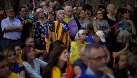 Independentistas catalanes escuchan a Carles Puigdemont en una pantalla de TV desde el Arco de Triunfo de Barcelona, el 10 de octubre de 2017