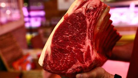 Un carnicero sujeta en la mano una pieza de chuletón Un carnicero sujeta en la mano una pieza de chuletón