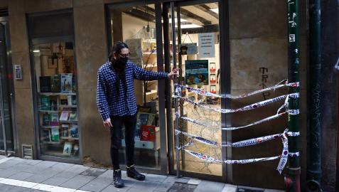 Manu Barceló, propietario junto a Pilar Escalada de la Librería Ménades, señala la puerta con el cristal roto