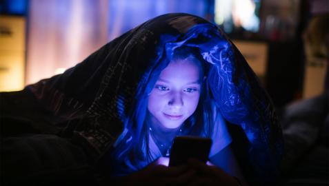pantalla Una niña mira una pantalla por la noche