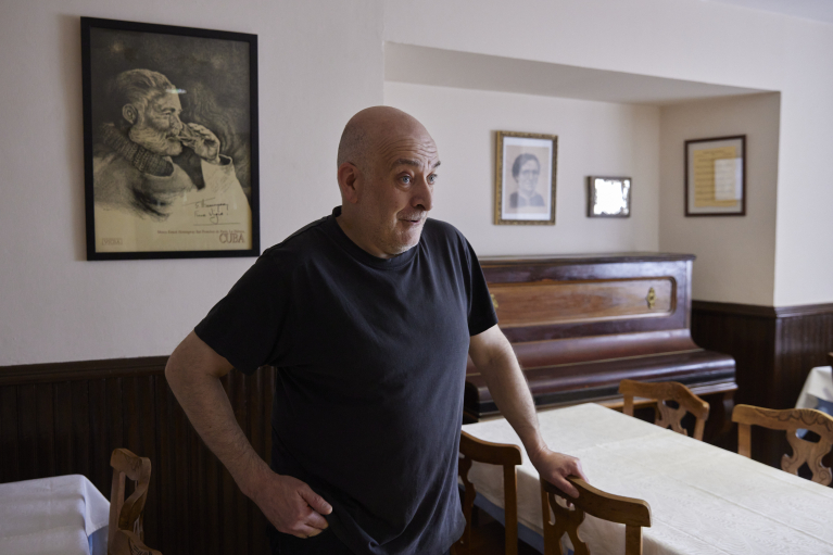 Hostal Iñaki Urdiroz, propietario del Hostal Burguete, en el comedor junto al piano y el cuadro de Hemingway. JESÚS GARZARON