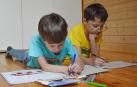Dos niños, uno de ellos con gafa, dibujan en el suelo