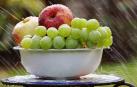 Un frutero con manzanas y uvas