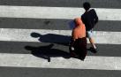 Dos personas caminan sobre un paso de peatones frente al Parlamento de Navarra, en Pamplona