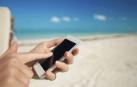 Una mujer usa el smartphone en la playa.