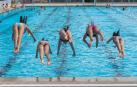 Un grupo de niñas saltando a una piscina.