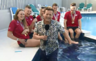 Entrevista a unos nadadores, tropieza y se sumerge en la piscina