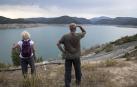 Dos personas contemplan  el bajo nivel del embalse de Itoiz, al 34% de su capacidad máxima.