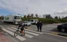 Un ciclista con la bici en la mano y dos peatones más cruzan por el paso de la carretera NA-2300 entre la rotonda de Sarriguren y el polígono Areta para llegar desde la Ciudad de la Innovación a Erripagaña.