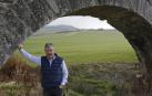 El presidente del sindicato UAGN, Félix Bariáin Zaratiegui, apoyado en un arco del acueducto de Noáin. Detrás, un campo de cereal recién brotado.
