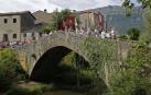 Vecinos de Uharte Arakil desfilan con la Virgen del Rosario por el puente medieval que salva el río Arakil.