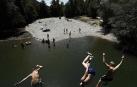 Varias personas se alivian del calor en el pantano de Alloz y en el río Arga a su paso por Irotz.