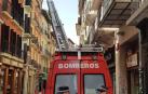 Los bomberos, durante la retirada del alero en mal estado en la calle San Antón.
