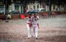 Dos personas, bajo la lluvia, en la Plaza del Castillo de Pamplona.