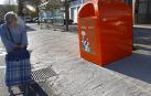 Una vecina de Pamplona pasea junto a un contenedor de reciclaje de aceite.