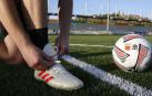 Un jugador juvenil del Burladés se ata las botas para empezar el entrenamiento.