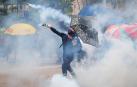 Un protestante antigubernamental arroja un bote de gas a los policía.