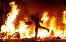 Un manifestante echa al fuego un cartón junto a la Delegación del Gobierno en Barcelona.