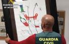 Un guardia civil sostiene una de las litografías robadas en Selva (Mallorca)