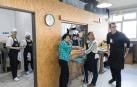 Varios voluntarios del comedor social Villa Javier Tudela se disponen a servir los platos a los usuarios.