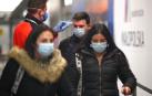 Un sanitario toma la temperatura a un joven en el aeropuerto de Cracovia.