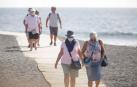 Varios turistas pasean este viernes por las inmediaciones del hotel en el que desde el pasado lunes permanecen incomunicados sus huéspedes y trabajadores al dar positivo en coronavirus cuatro de los que se alojaban en el centro turístico de Adeje, en el sur de Tenerife.