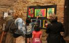 Padres y alumnos contemplan una exposición de pintura abstracta realizada por escolares.