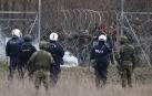 Un grupo de migrantes intenta de cruzar la frontera griega, mientras la policía trata de evitarlo lanzando botes de gases lacrimógenos