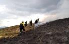 Bomberos trabajan en una quema de pastos de montaña.
