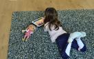 Una niña lee en el salón de su casa.