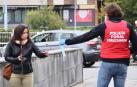 Un policía foral reparte una mascarilla a una mujer.