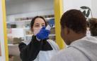 Una voluntaria toma la temperatura a un usuario antes de entrar a 'El Capacico'.