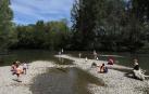 Disfrutar del sol e incluso refrescarse a la orilla del río Arga alivió del calor a decenas de personas.