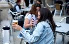 Una joven saca una fotografía a su cerveza en una terraza.