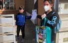 Una voluntaria entrega el diploma y mascarillas a un niño.