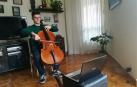 El pamplonés Fermín García Menéndez, de 19 años, tocando el violonchelo frente a la pantalla de su ordenador portátil.