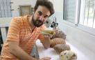 El investigador Daniel Barasoain, en el laboratorio CECOAL de Corrientes, en Argentina, donde trabaja y estudia los armadillos fósiles. Sujeta en su mano en un tipo de armadillo actual, el pichiciego.