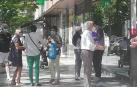 El vigilante de seguridad informa a un contribuyente de las reglas para ser atendido mientras otro grupo de afectados comparte su malestar.