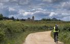 Un ciclista circula por una pista del entorno de Ayegui que lleva hasta el Monasterio de Irache, al fondo de la imagen.