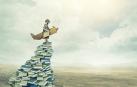 Imagen de un lector sobre una montaña de libros