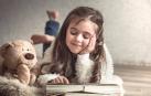 Imagen de una niña leyendo sobre la cama