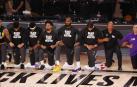 Los jugadores de Los Angeles Lakers y Los Angeles Clippers escuchan el himno con la rodilla en el suelo contra el racismo