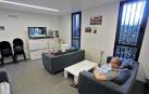 Usuarios del centro para personas sin hogar de Triniarios ven la televisión guardando la distancia.