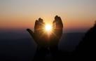 Imagen de dos manos que parecen encerrar el Sol