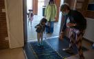 Daniela, de 4 años, desinfecta sus zapatos tras soltar a su madre, con abrigo amarillo, Marta Sampedro.